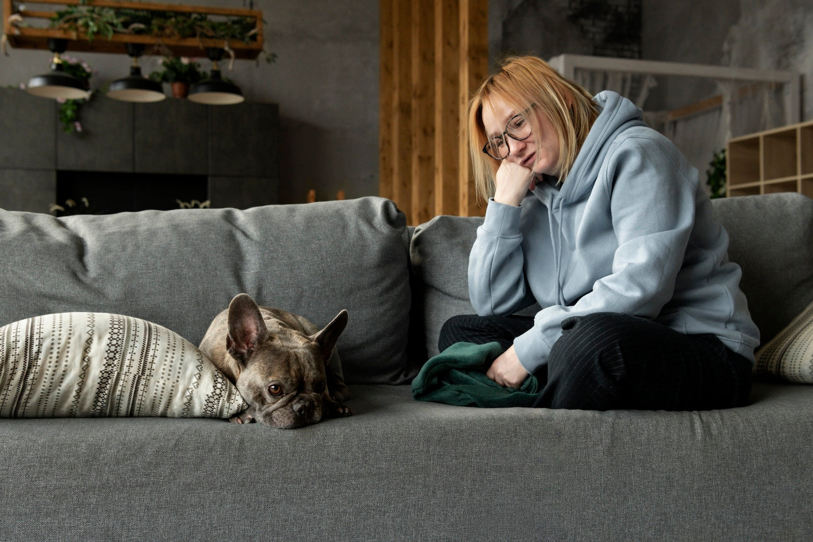 Dog owner sitting beside her French bulldog at home, highlighting how dogs provide emotional support and help reduce stress.