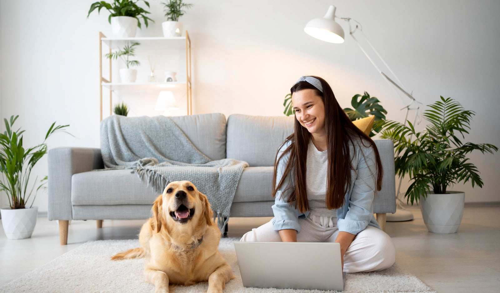 Dog owner relaxing at home with her golden retriever while using a laptop, illustrating responsible dog ownership and everyday pet care habits that support cleaner communities.