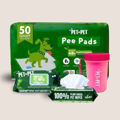 Pet N Pet product bundle on a bright green background, featuring a 50-count pack of 22x23 inch training pads (48% plant-based), a pack of 100 unscented 100% plant-based pet wipes, and a blue Pet N Pet poop bag dispenser with a wrist strap.