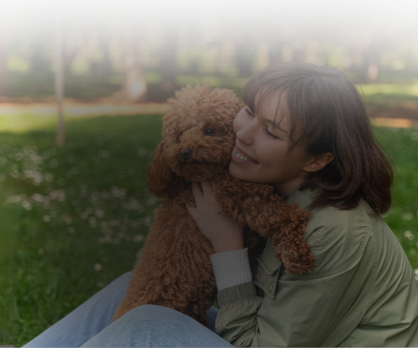 Woman holding a brown dog in a park