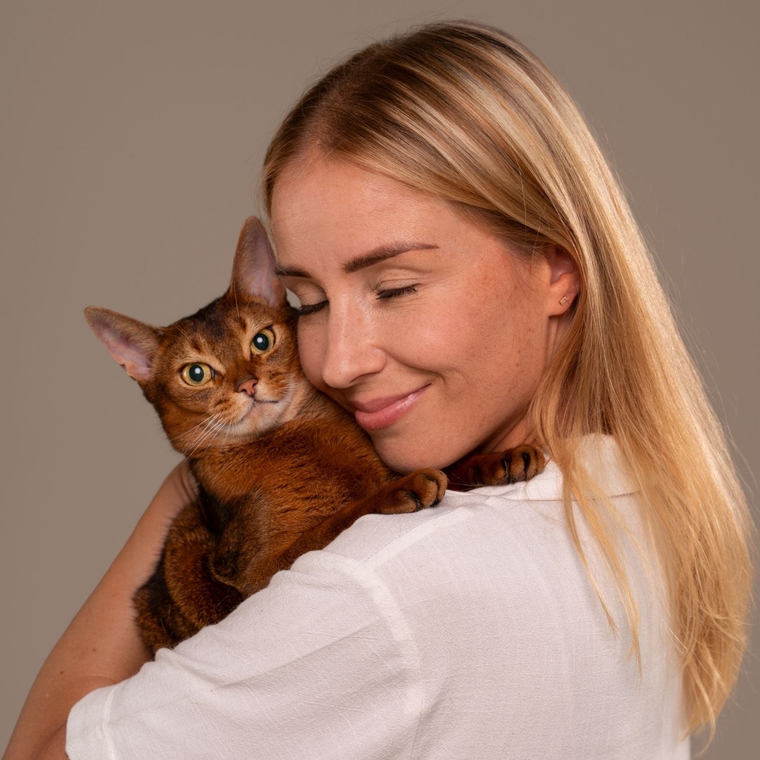 Woman holding a cat against a plain background